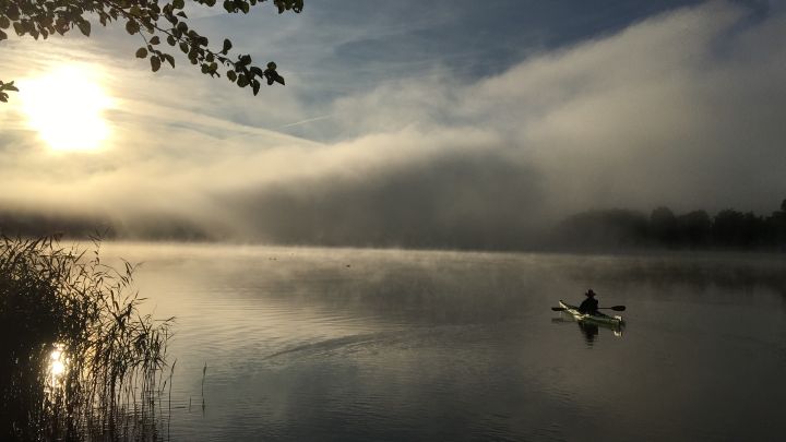 Paddler auf dem Gobenowsee am Morgen zwischen Sonne und Regenfront.